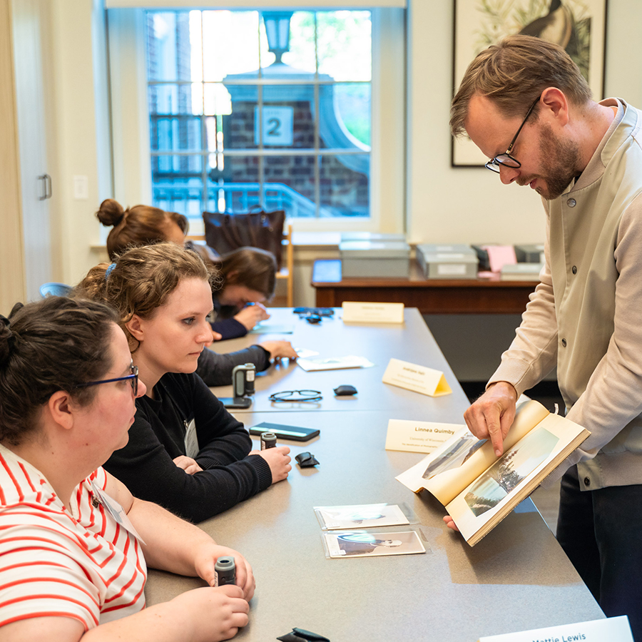 Teacher walking around classroom showing off prints in a book to students