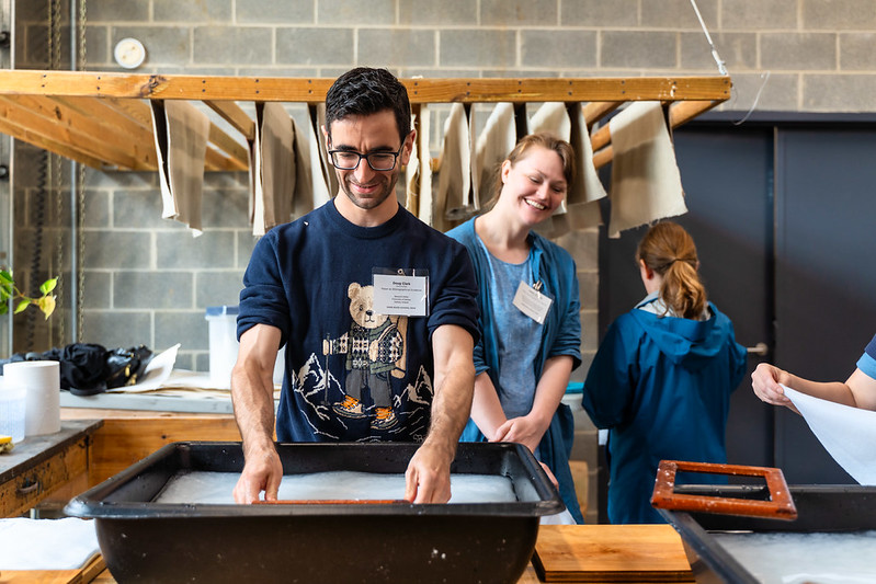 Man with hands in tub in a papermaking workroom