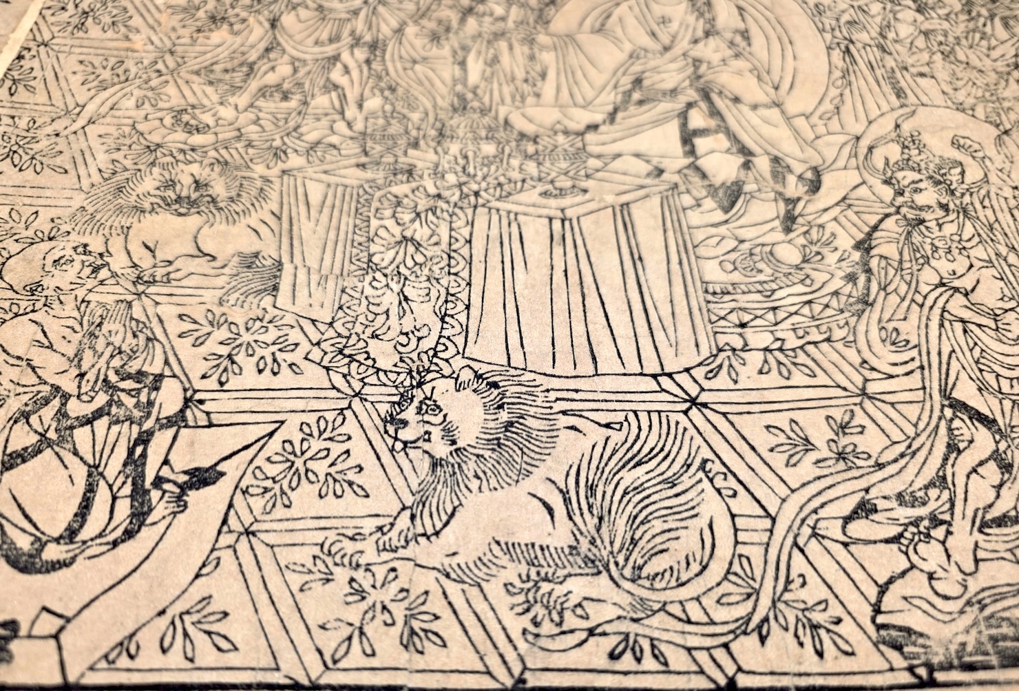 An East Asian line drawing showing a lion-like animal in the middle of a busy scene with various people and holy figures