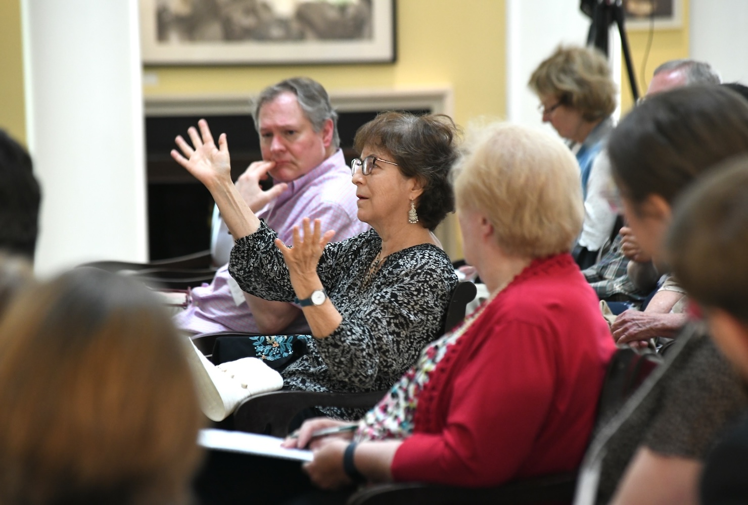 A woman gestures as she asks a question in an audience of seated people