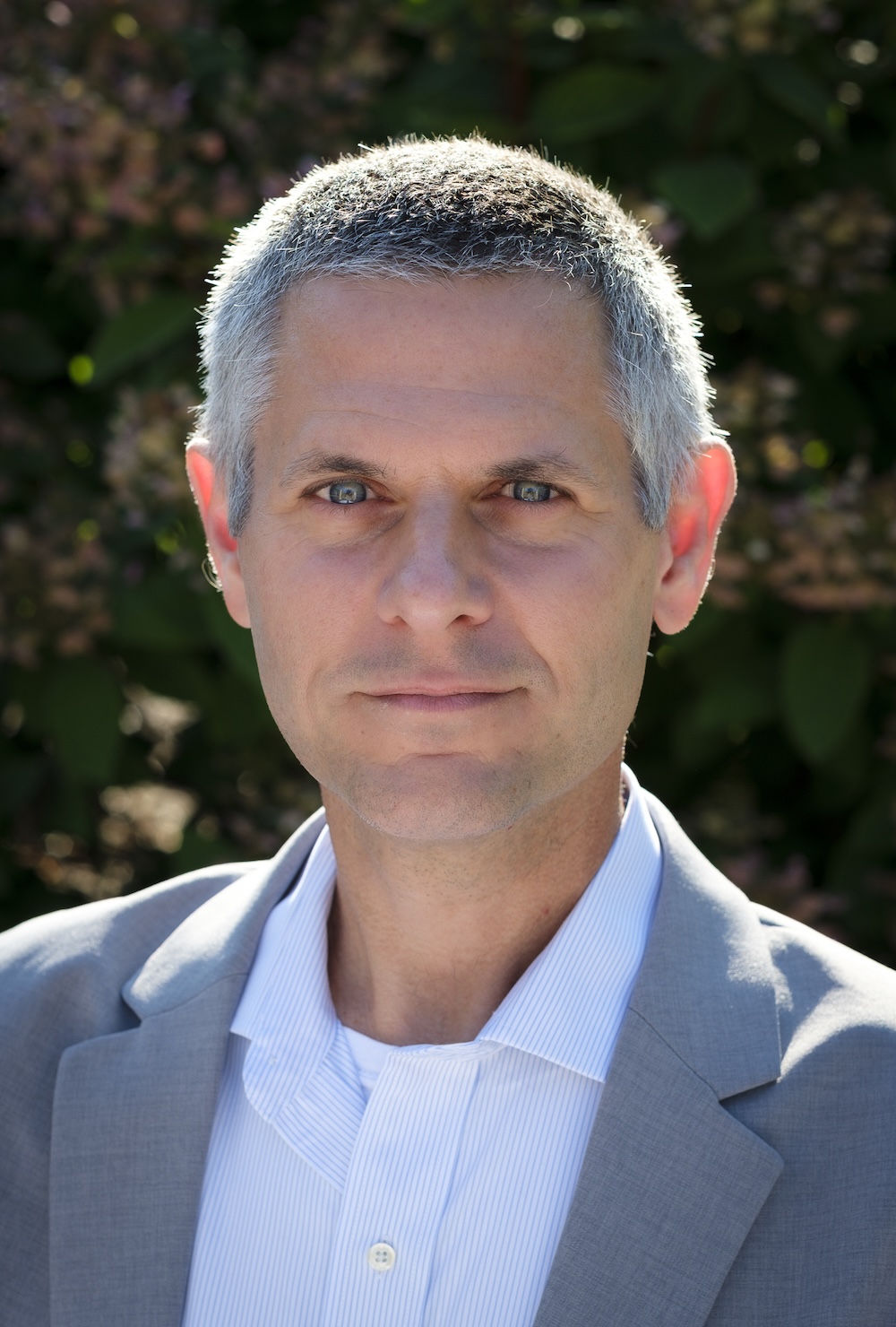 Headshot of a man with a gray suit jacket over a collared shirt.